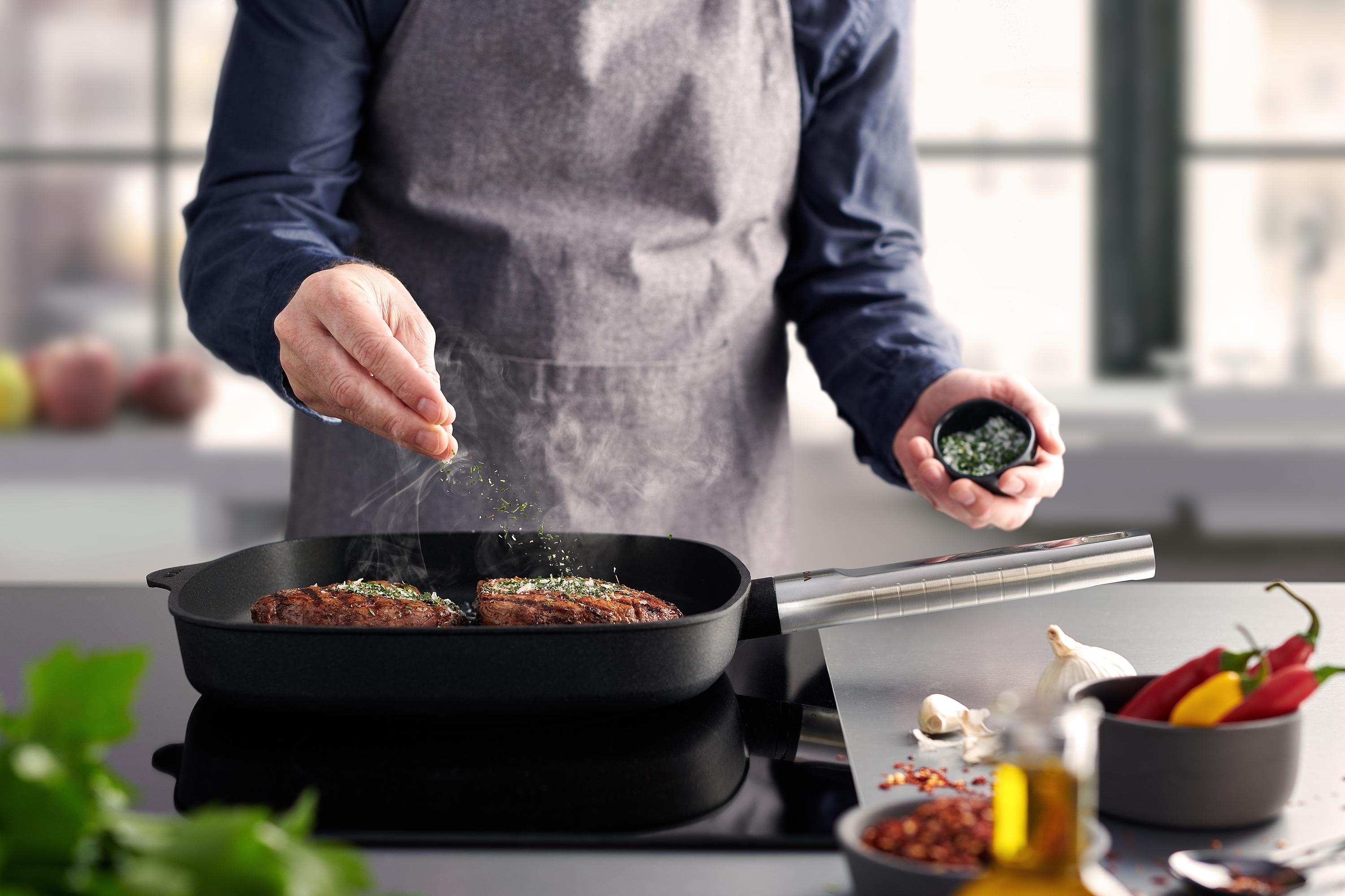 In einer runden Logic XR Pfanne wird Fleisch angebraten und mit Salz verfeinert.