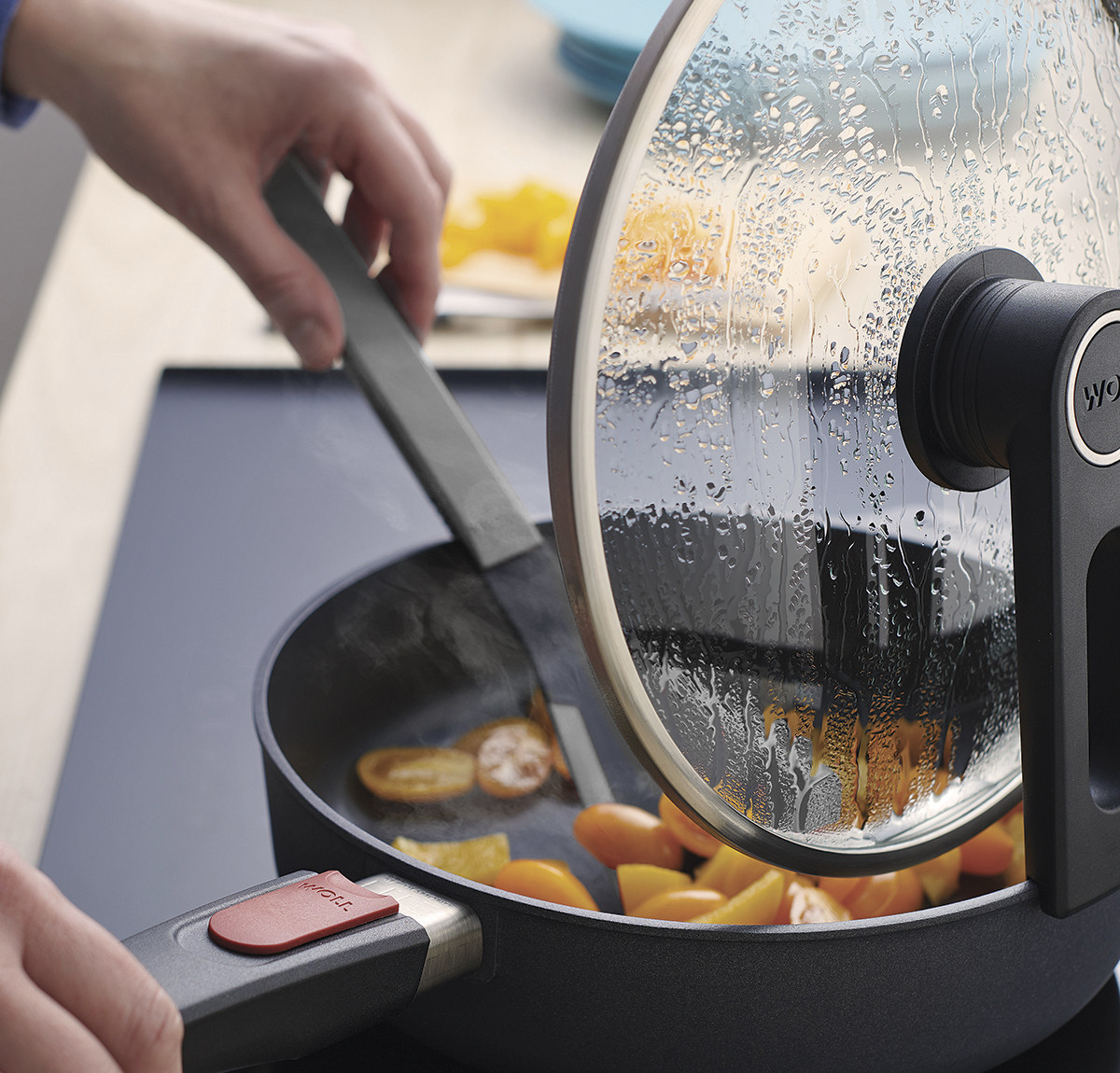 Cook it Pfannenwender In der runden Diamond Lite Pfanne wird ein Gericht mit einem grauen Cock it Pfannenwender umgerührt. Der Smart Lid steht auf der Pfannenkante.