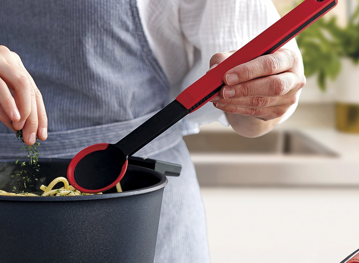 In einem Diamond Lite Topf werden frisch gekochte Nudeln mit einem roten Kochlöffel  der Serie Cock it umgerührt und mit Kräutern garniert.