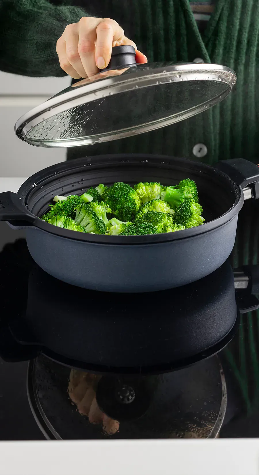 In der Nahaufnahme ist der runde, multifunktionale Silikoneinsatz der Serie „Steam it” zu sehen, der im Topf platziert ist, in dem der frische Brokkoli gedämpft wird. Der Glasdeckel wurde entfernt.