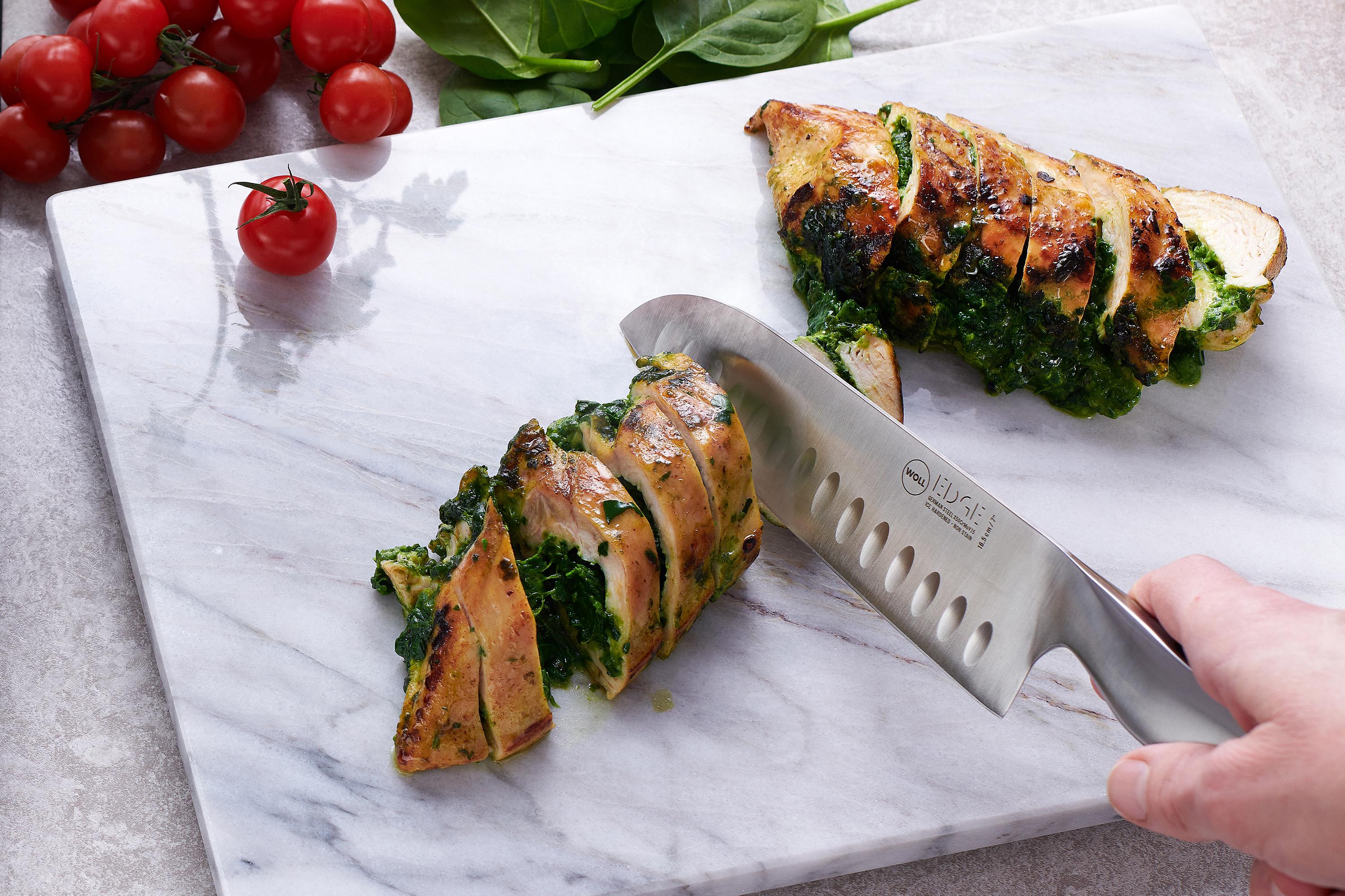 Mit dem Edge Santokumesser wird eine mit Spinat gefüllte Fleischrolle in Portionsgrößen geschnitten.