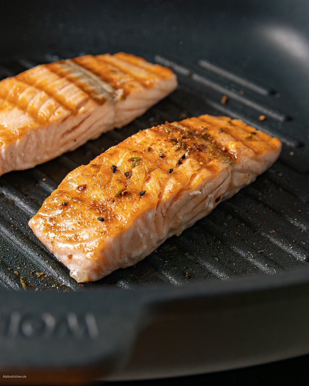 In einer viereckigen Titan Best Grillpfanne mit Rillen wird Lachs angebraten.