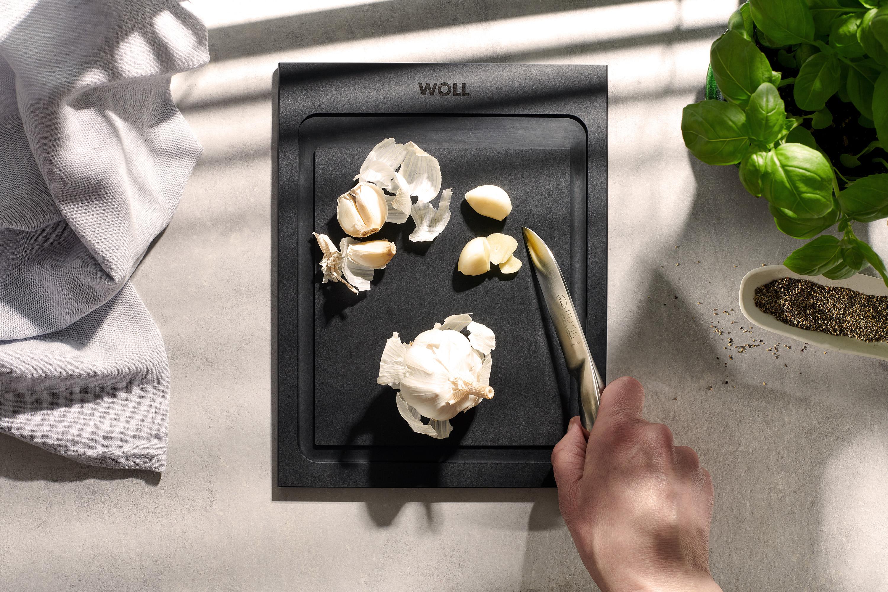 Auf einem Cut & Serve Schneidebrett mit Saftrinne liegen Knoblauchzehen. 