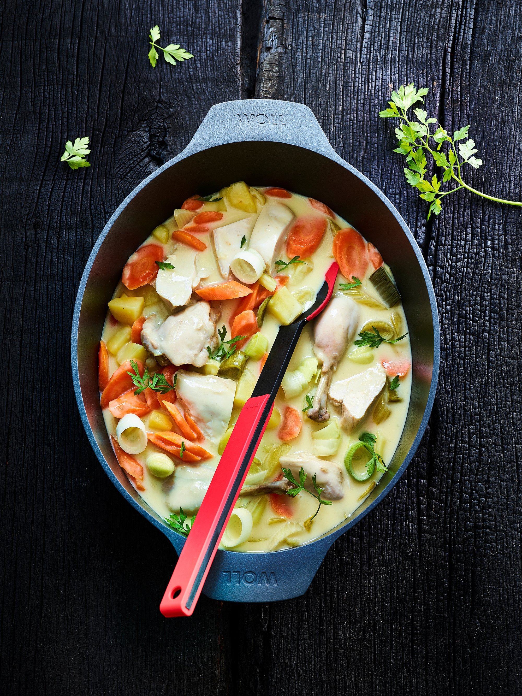 Diamond-Lite_3126DPI_beschwipstes_huhn_RGB In einem Diamond Lite Bräter befindet sich Geflügel und Gemüse. Mit einem Cock it Küchenhelfer wird alles umgerührt.