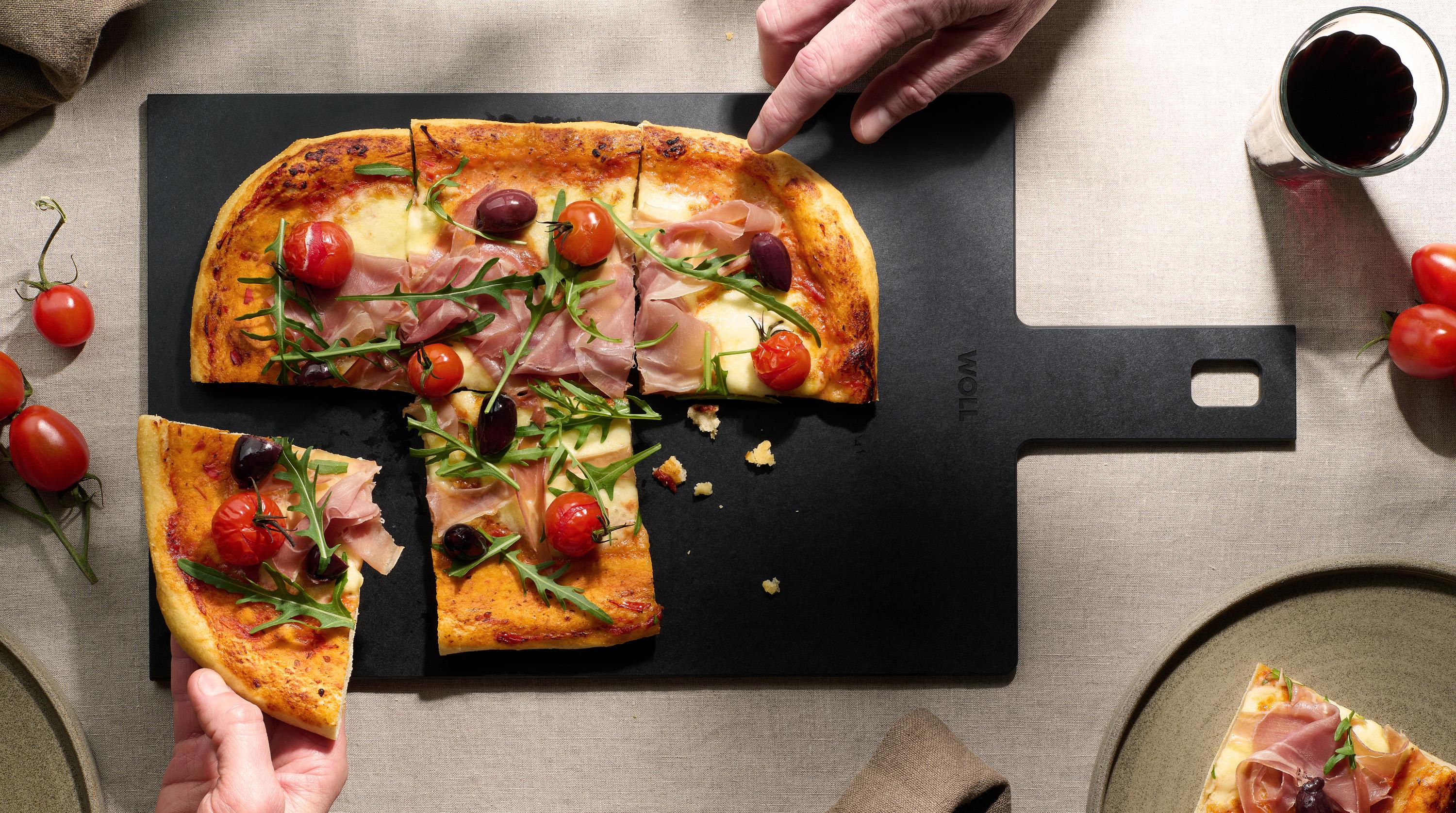 Cut & Serve Schneidebrett mit Griff Auf dem Cut & Serve Schneidebrett mit Griff liegen frisch gebackene Pizzastücke.