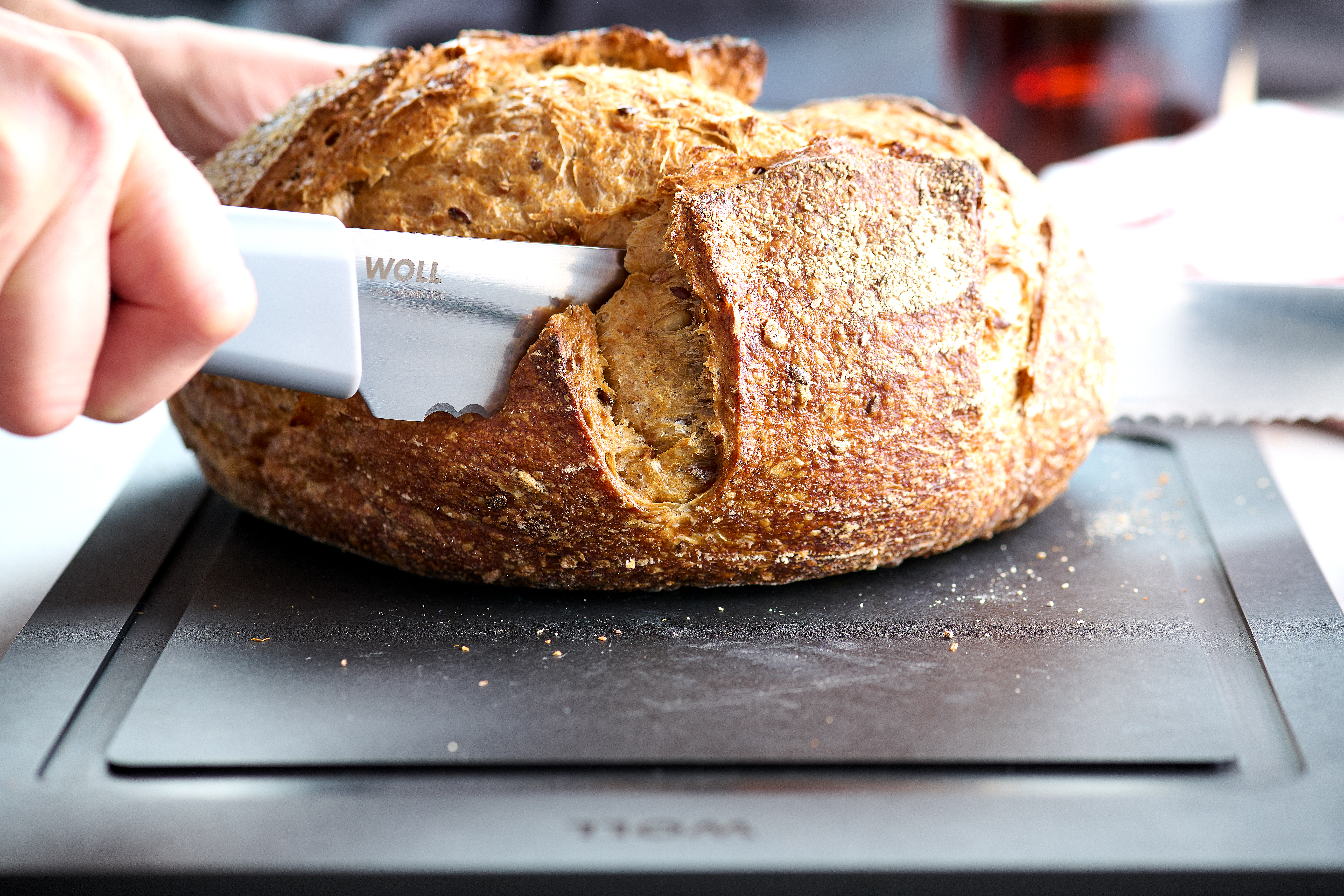 Mit einem Cutting Edge Messer wird ein Brotlaib auf einem Cut & Serve Schneidebrett geschnitten.