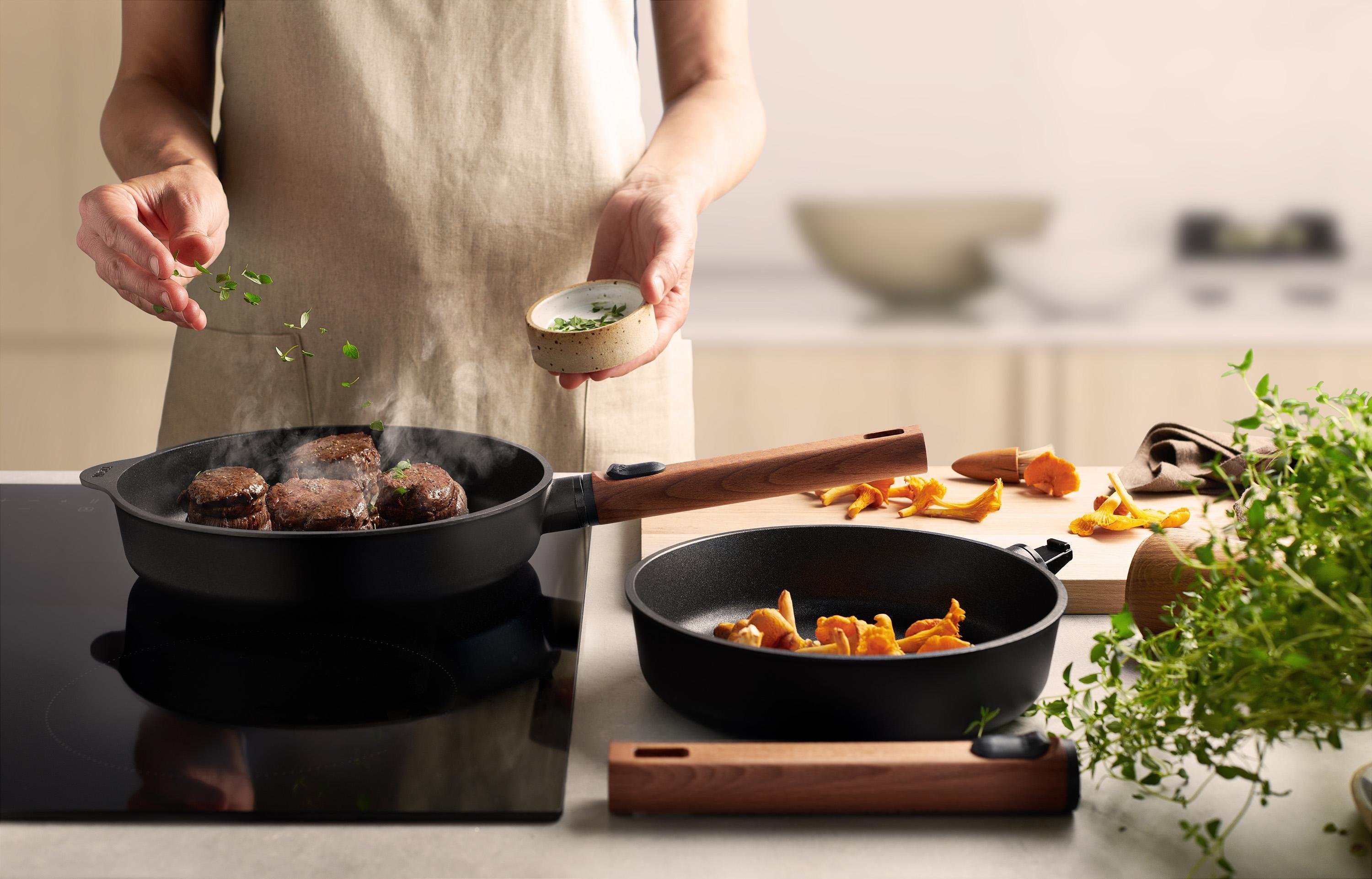 In einer runden Eco Logic QXR-Pfanne wird Fleisch angebraten. In der Pfanne daneben liegen Pfifferlinge.