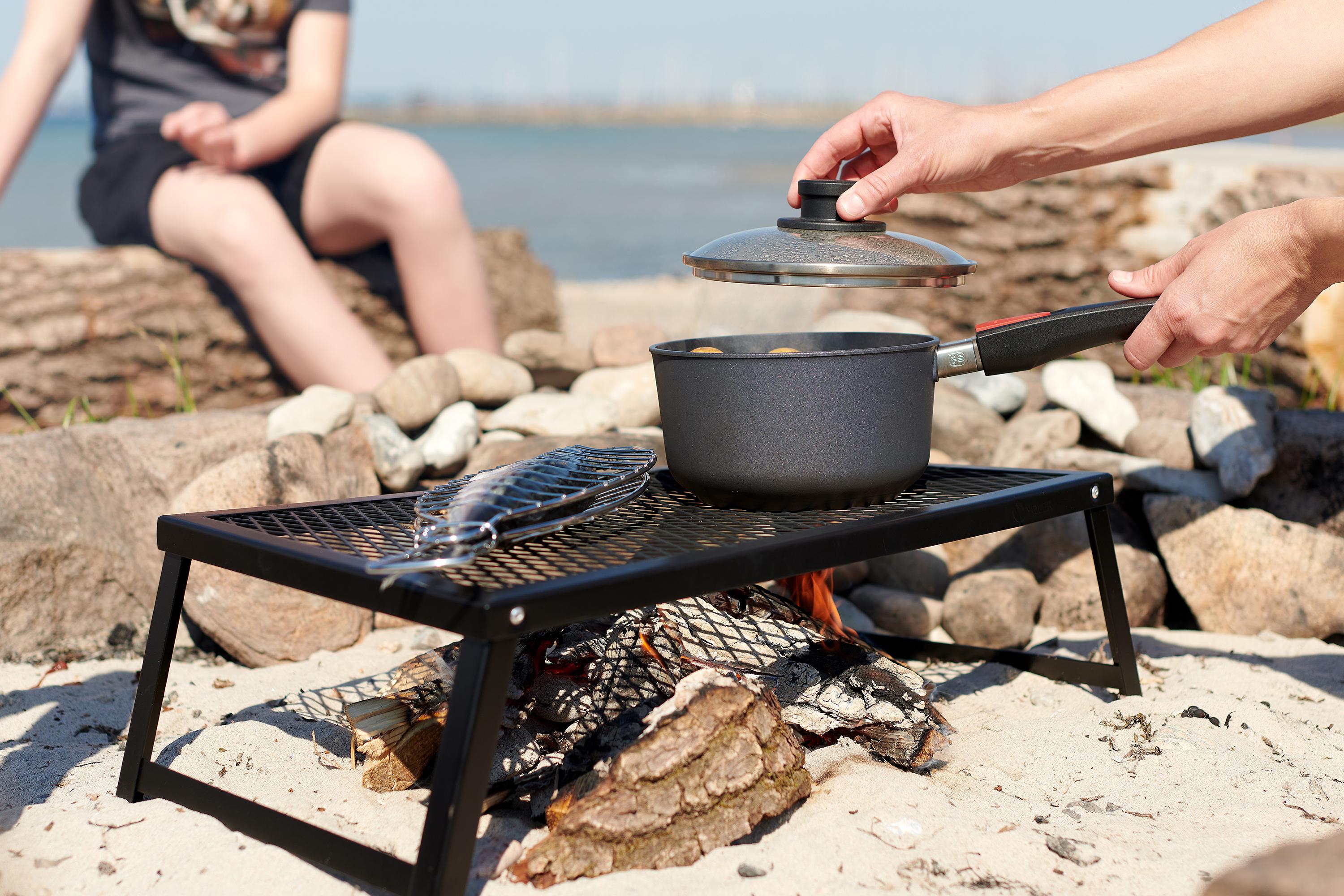 Auf dem Grill steht ein Diamond Lite Topf, in diesem befindet sich ein dampfendes Gericht. Der Glasdeckel wird hochgehoben.