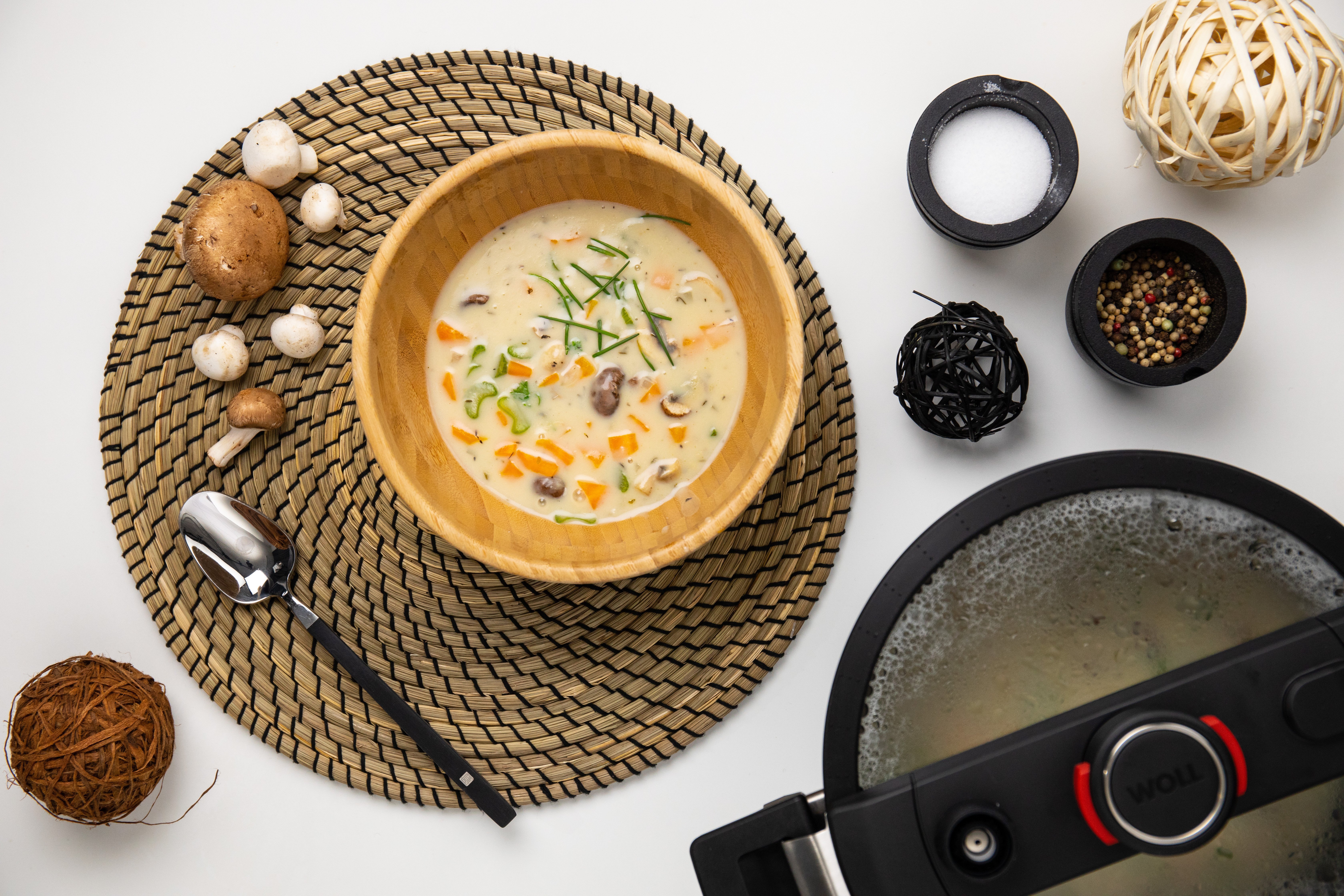 In einer runden Schüssel befindet sich frisch gekochte, cremige Pilzsuppe mit Reis. Daneben steht der runde Niederdrucktopf der Serie Diamond Active Lite, in dem die Suppe zubereitet wurde.