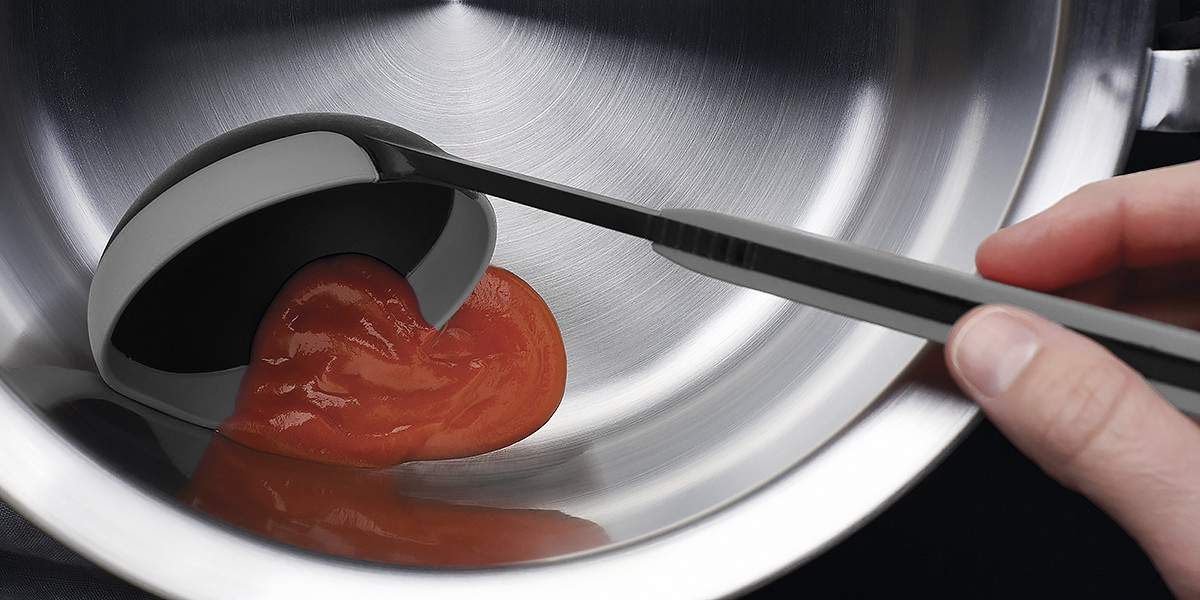 Cook it Schöpfkelle Die Tomatensoße wird mithilfe der grauen Cock it Schöpfkelle in eine silberne Schüssel gegeben.