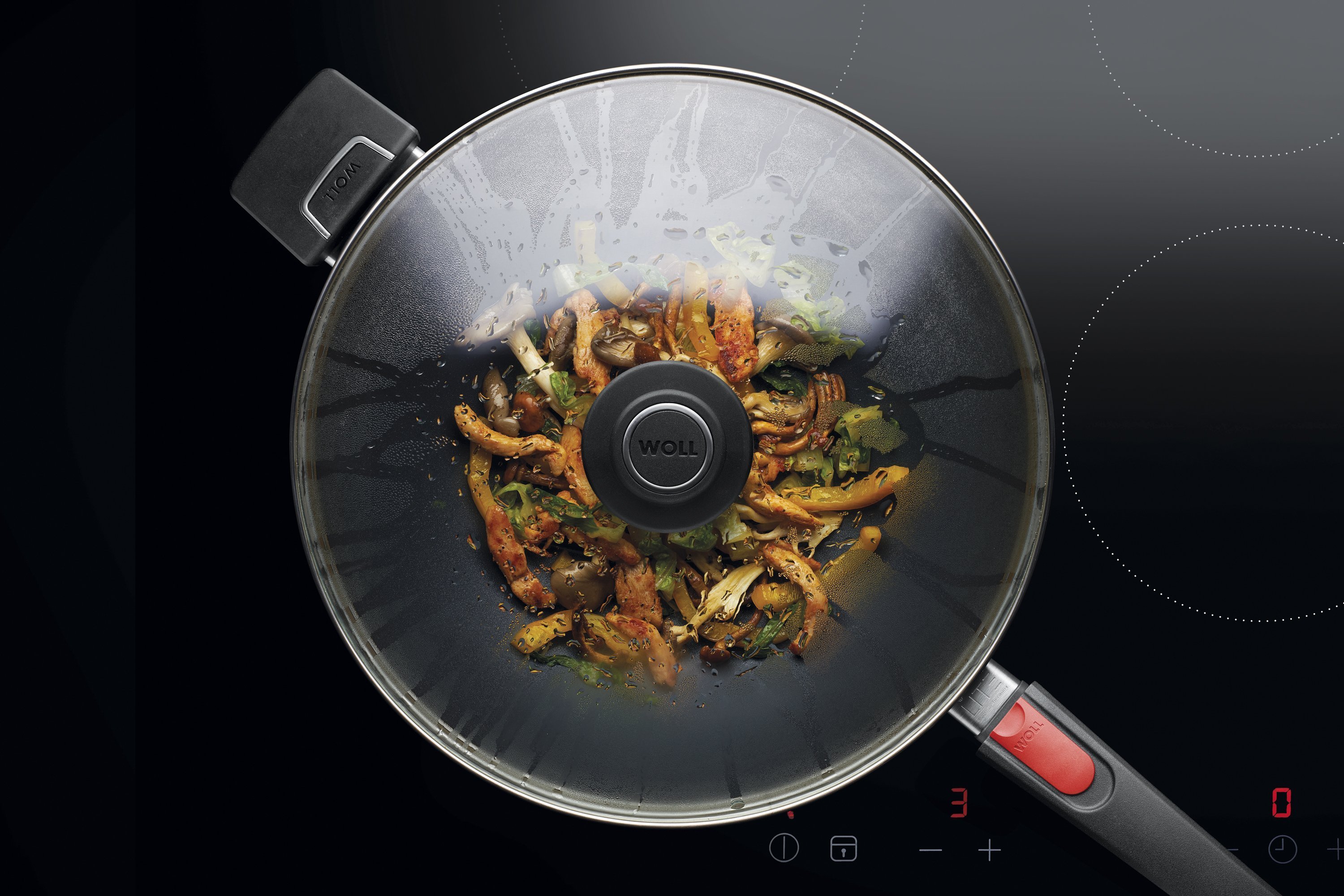 Sicherheitsglasdeckel, rund Auf dem Herd steht eine runde Diamond Lite Wok- und Rührpfanne In dieser befindet sich ein frisch zubereitetes Gericht. Am Glasdeckel hat sich Kondenswasser gebildet.