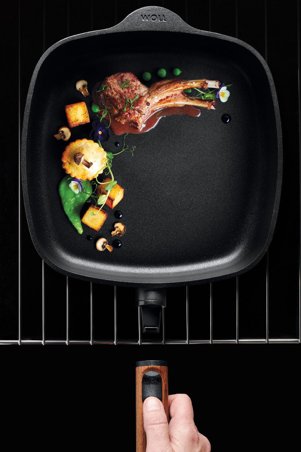 Eco Logic QXR Guss-Viereckpfanne Auf dem Backofenrost steht eine runde Eco Logic QXR Pfanne mit angebratenem Fleisch. Um die Pfanne zu entnehmen, wird der Stiel eingerastet.