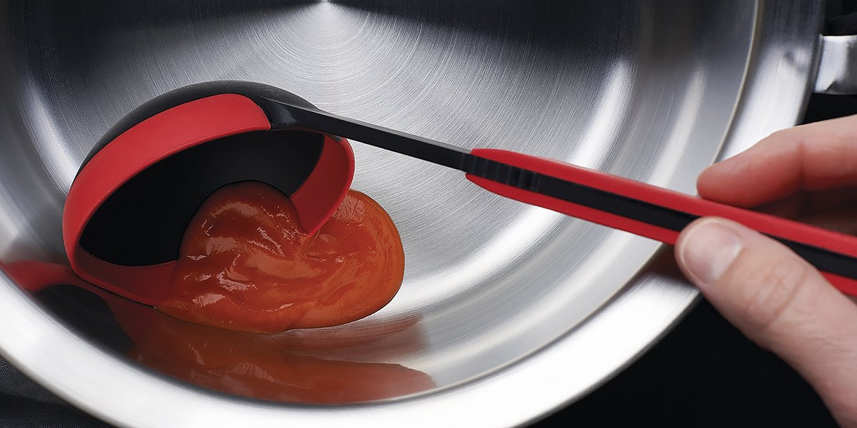 KU008_Mood_1200x600_RGB Die Tomatensoße wird mithilfe der roten Schöpfkelle aus der Serie Cock it in eine silberne Schüssel gegeben.