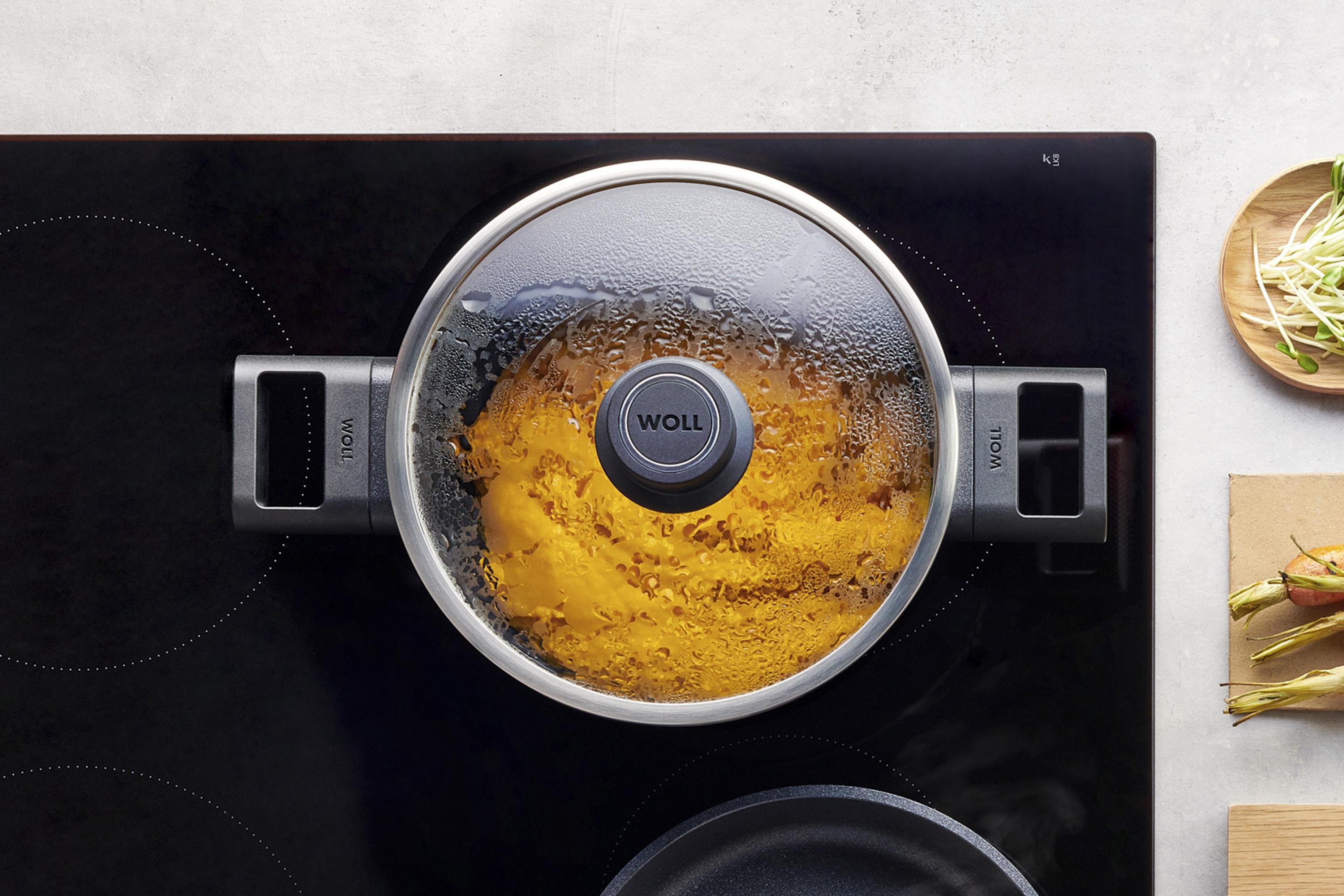 Auf dem Herd steht ein runder Eco Logic QXR Topf, in dem sich ein dampfendes Gericht befindet. Am Glasdeckel hat sich Kondenswasser gebildet.