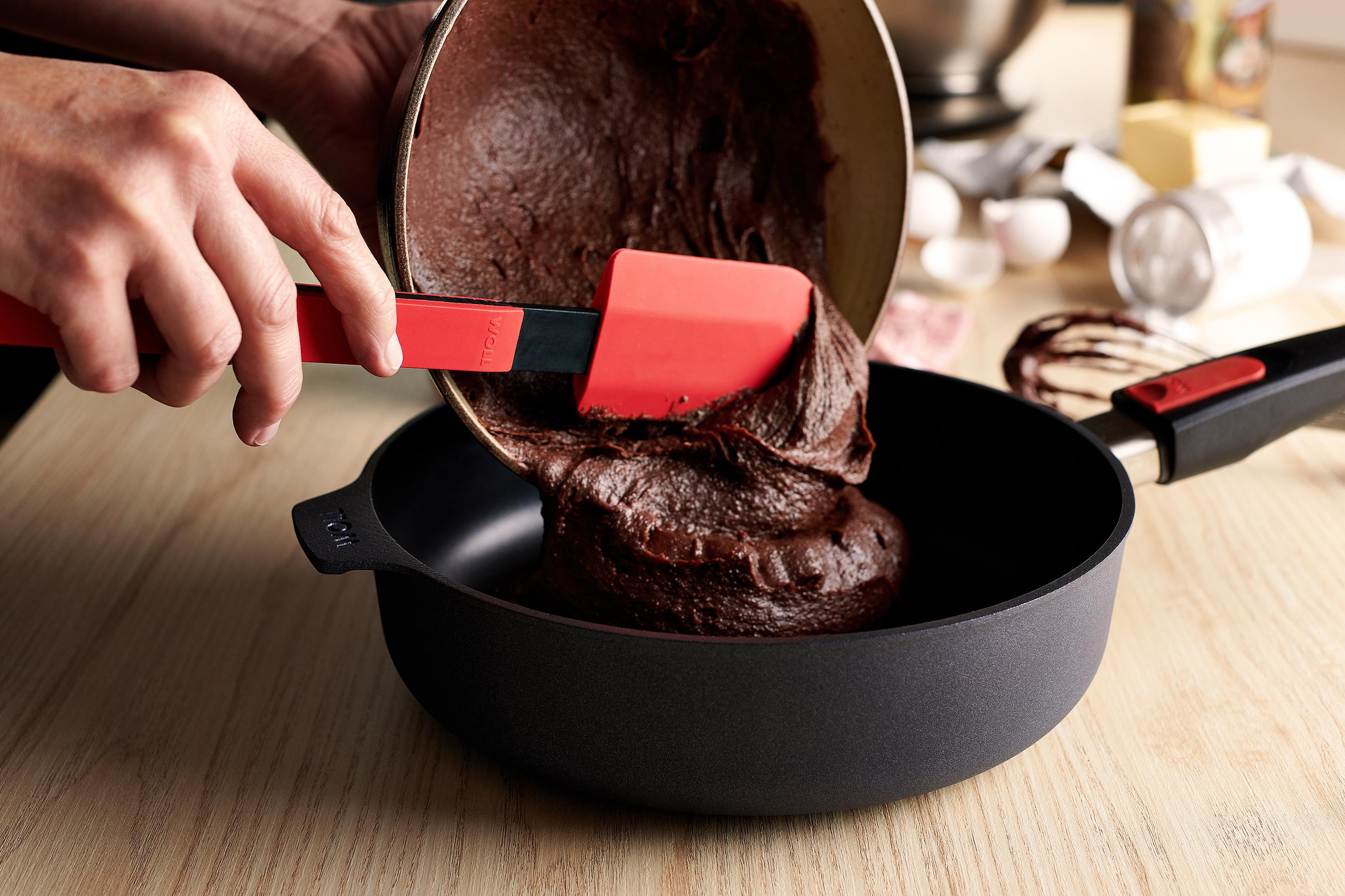 Der Kuchenteig wird mit einem roten Cook-it-Teigschaber aus der Schüssel direkt in die Diamond Lite Hochrandpfanne gegeben.