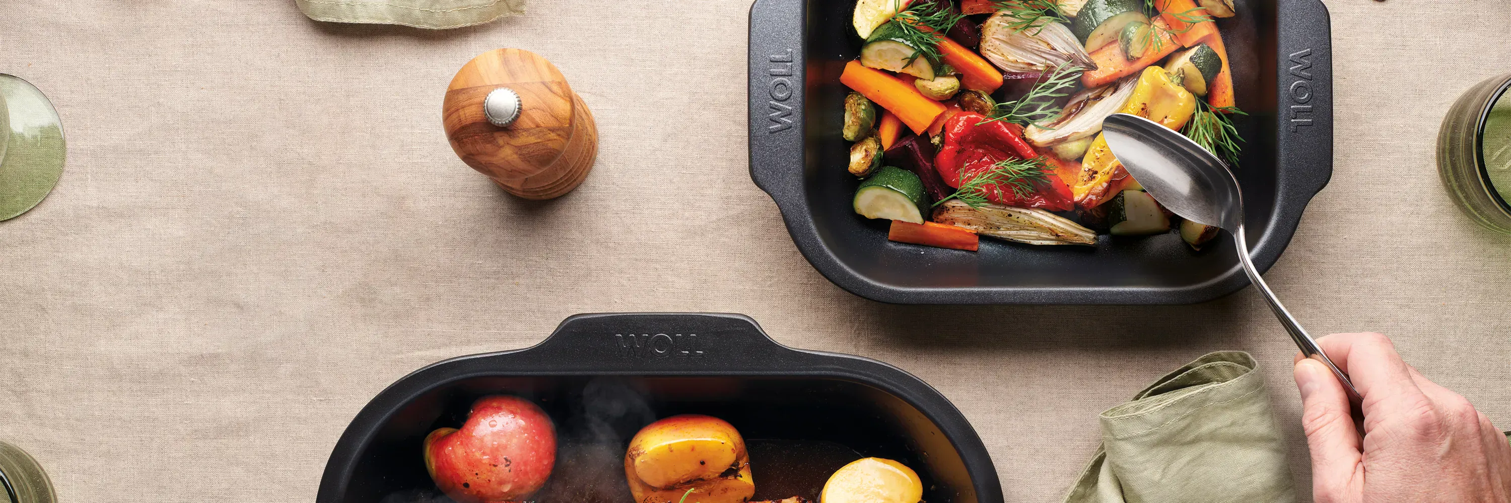 Auf dem Tisch stehen zwei heiße, viereckige Bratreine der Serie Roast it!, in denen sich dampfende Gerichte befinden.