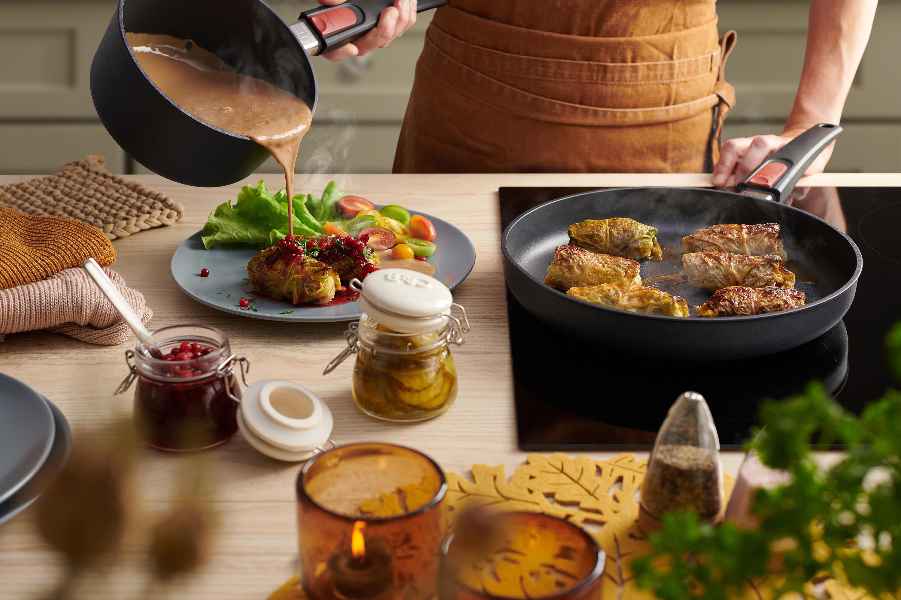 In einer runden Diamond Lite Pfanne werden schwedische Kohlrouladen angebraten und auf einem Teller platziert. Mit einem Stieltopf wird Soße über die Kohlrouladen gegossen.