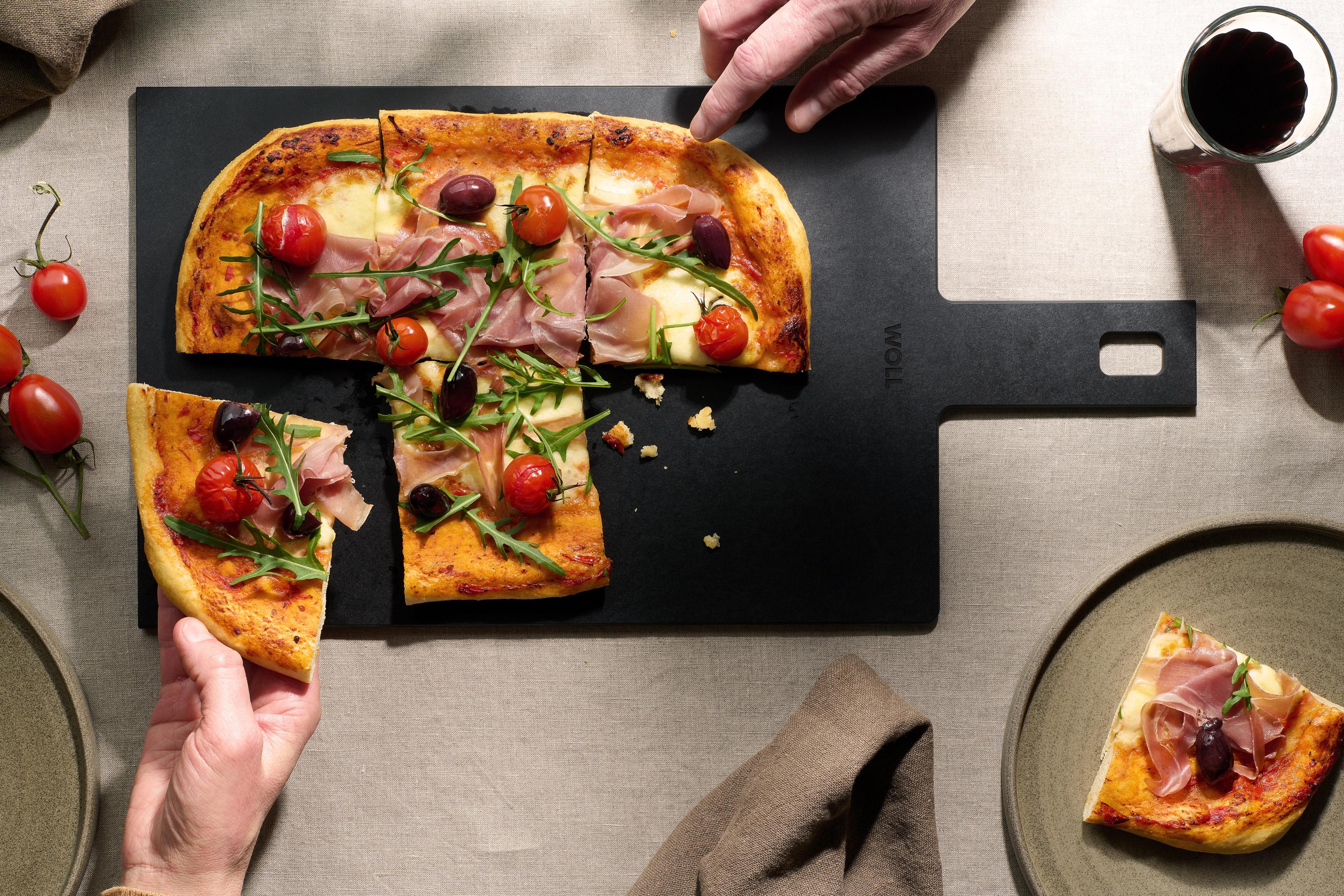 Auf dem Cut & Serve Schneidebrett mit Griff  liegen frisch gebackene Pizzastücke. 