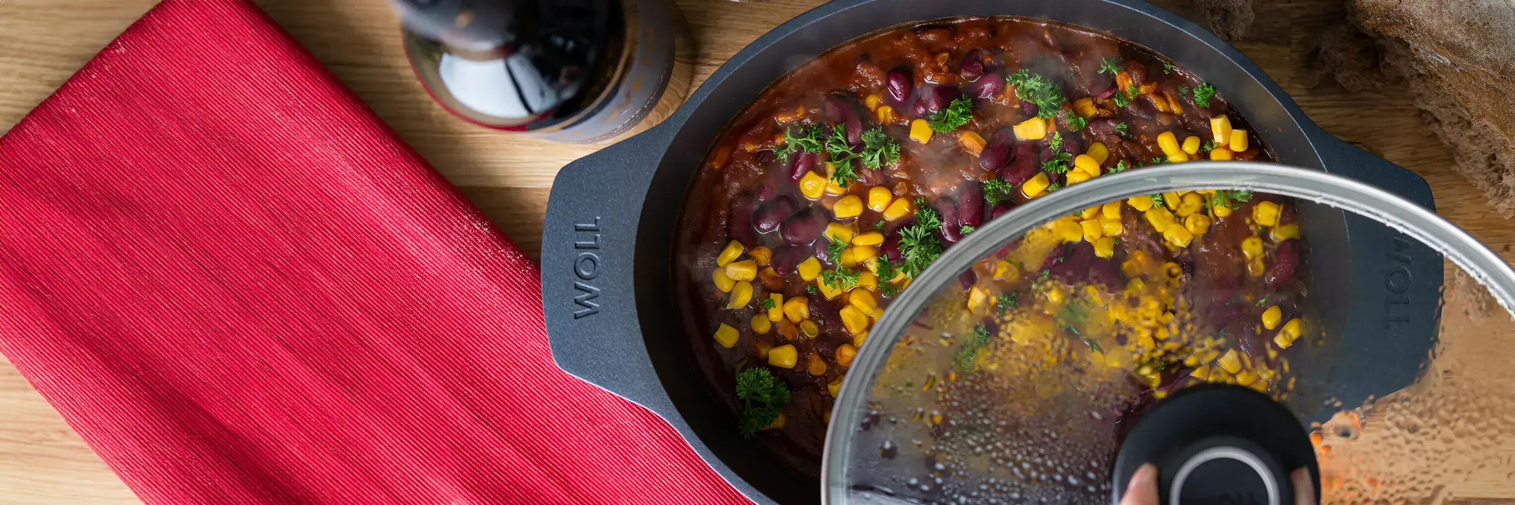 Ein Gussbräter der Serie Diamond Lite enthält Chili Sin Carne, daneben steht eine Flasche und ein rotes Tuch liegt daneben.