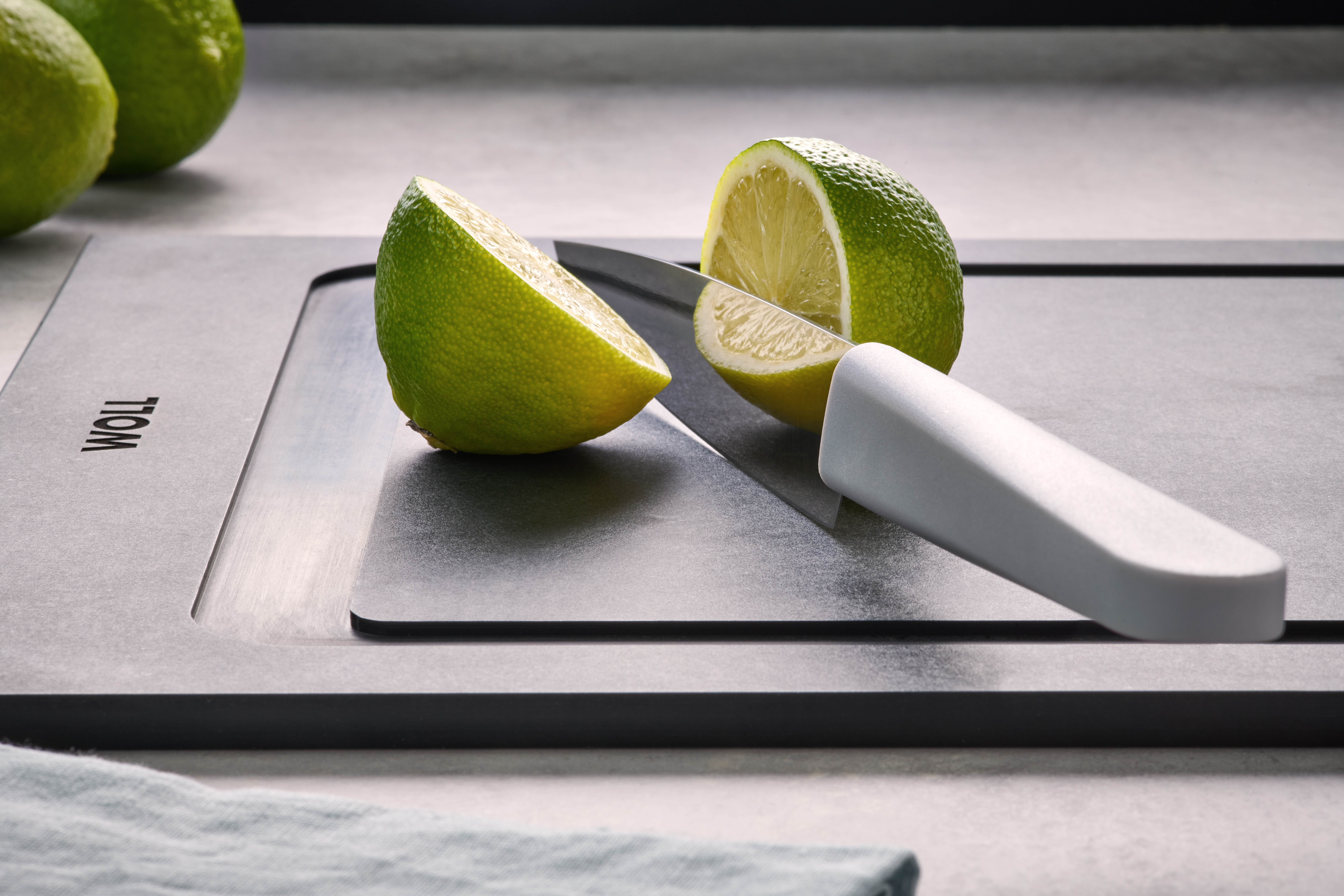 Cutting Edge Universalmesser Eine Limette wurde mit einem Cuting Edge Messer auf einem Cut & Serve Schneidebrett halbiert.