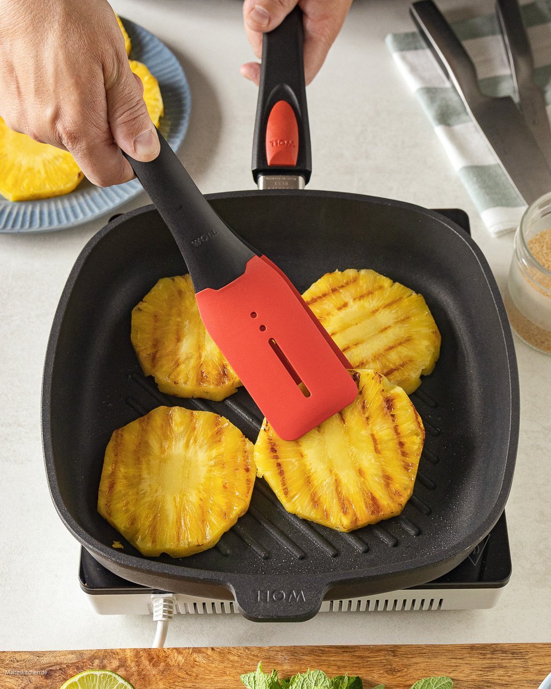 Titan Best Guss-Grillpfanne, viereckig, mit Rillen In einer viereckigen Titan Best Pfanne werden Ananasscheiben angebraten und mit einer Cock it Küchenzange gewendet.