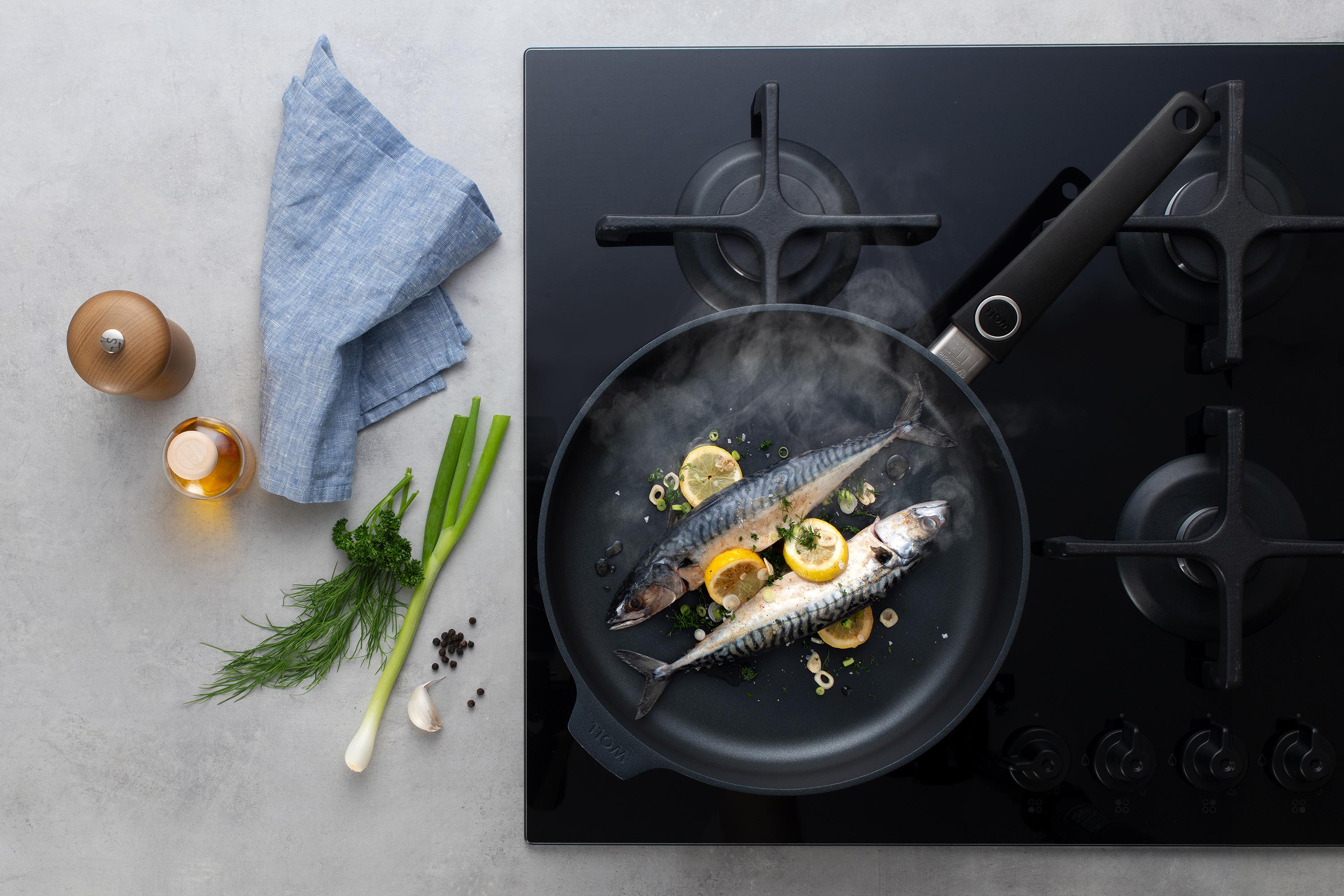 Diamond Lite Guss-Hochrandpfanne In einer runden Diamond Lite Pfanne wird Fisch mit Zitrone und Frühlingszwiebeln zubereitet. Am Glasdeckel hat sich Kondenswasser gebildet.