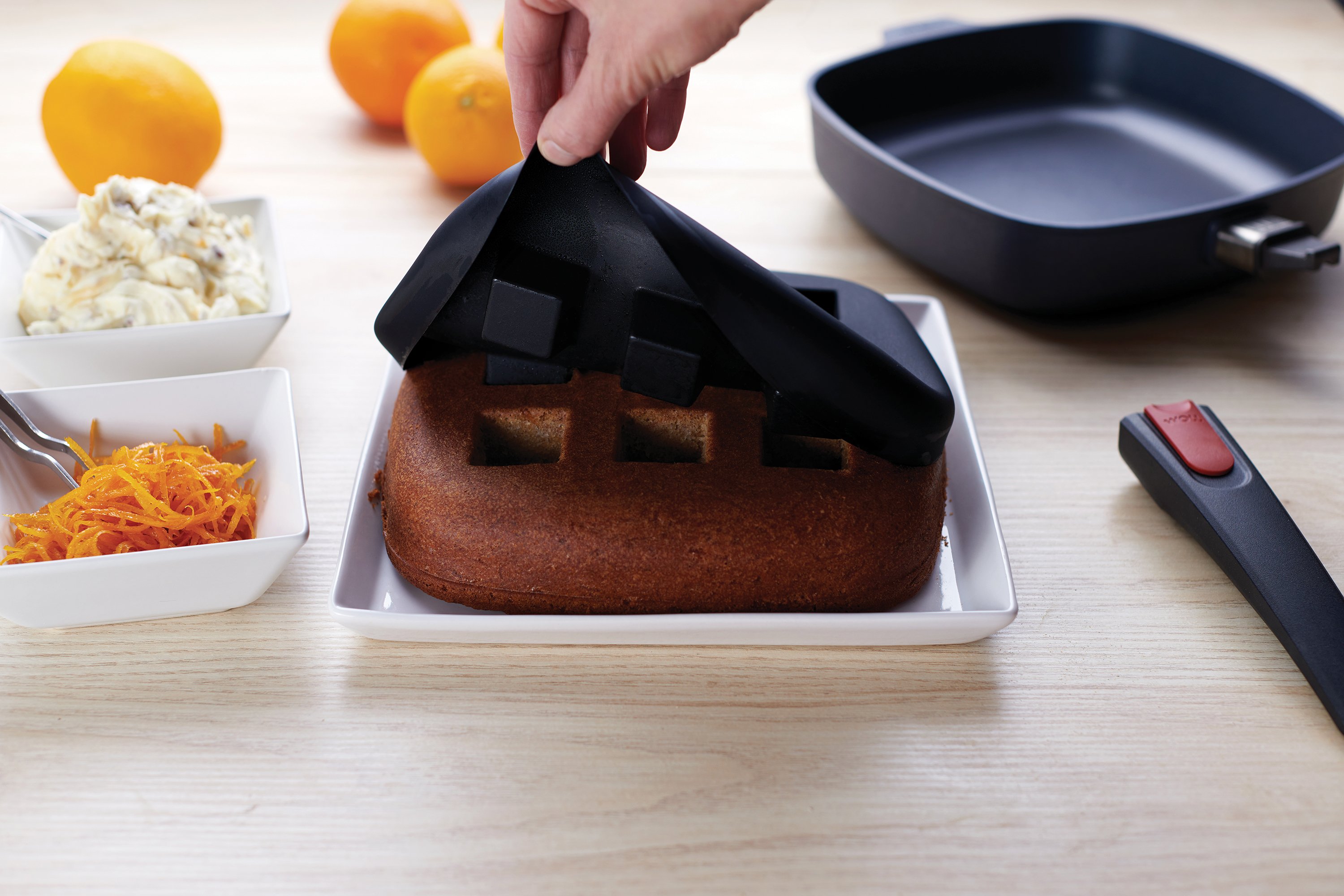 Auf einem Teller steht ein frisch gebackener Kuchen, der aus dem viereckigen Bake it Silikon-Backeinsatz genommen wurde.