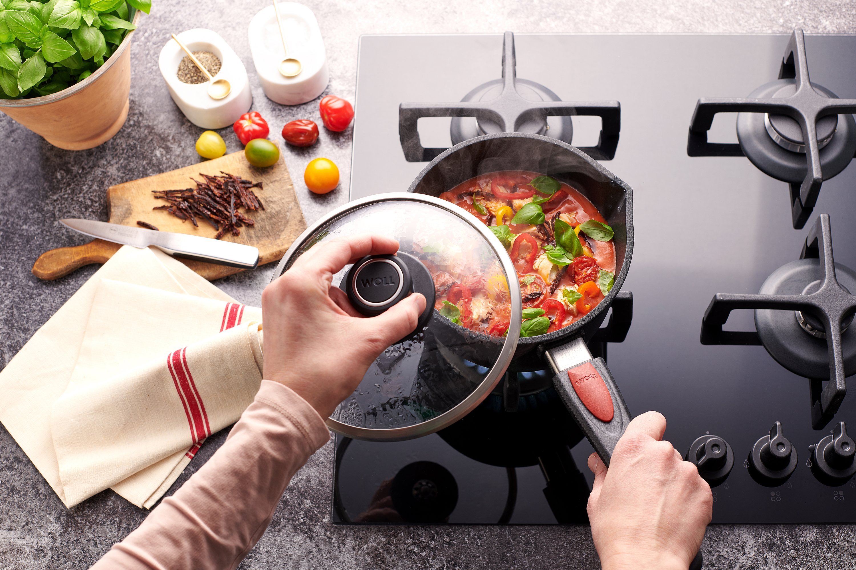 In einem Titan Best Stieltopf mit abnehmbarem Stiel wird eine Quattro Tomatensuppe mit Paprika und gegrilltem Hähnchen zu bereitet.Der Deckel wurde abgenommen. Außerhalb des Kochfelds liegen weitere Zutaten.