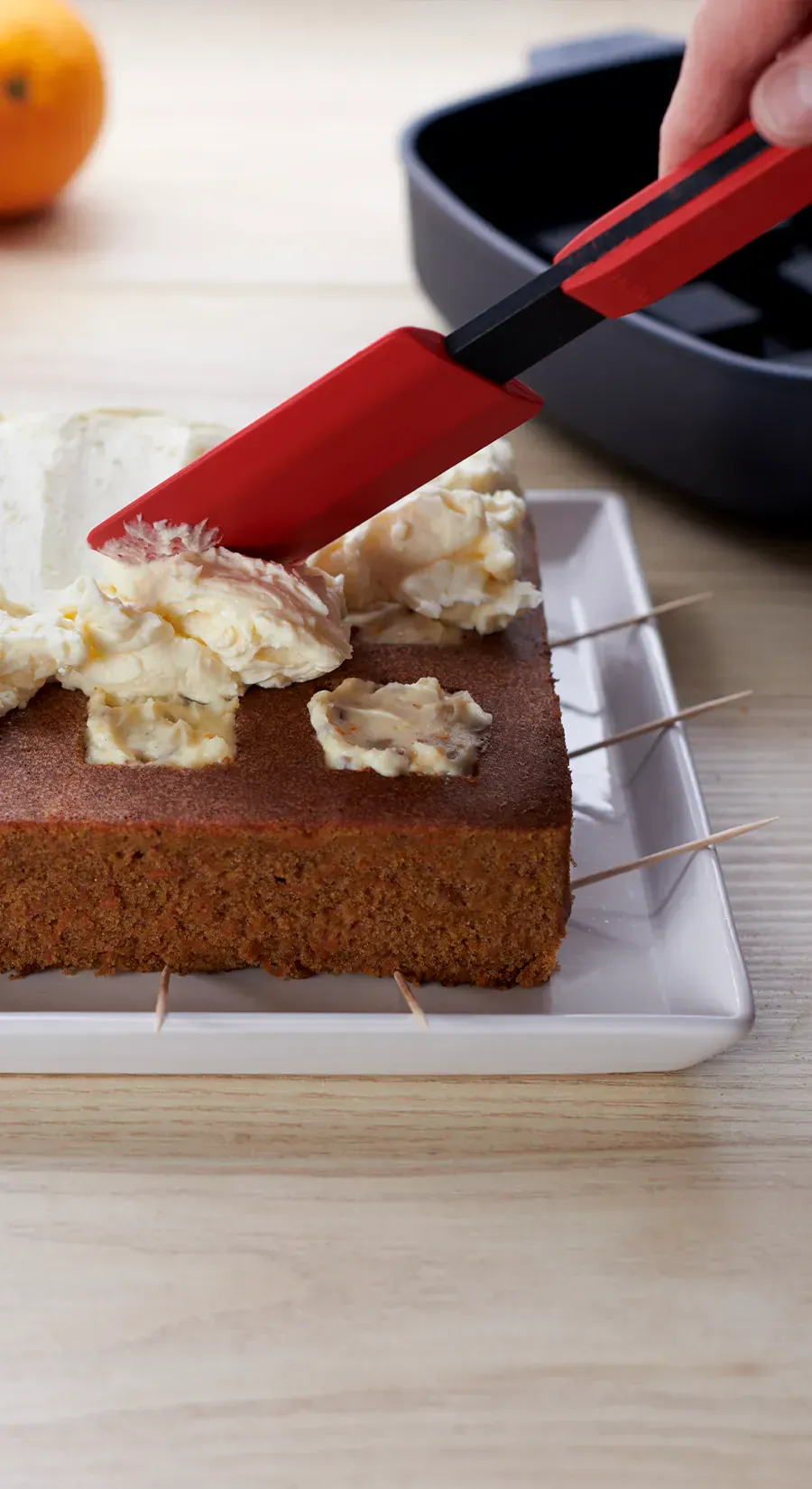 Mit dem Teigschaber von Cock it wird die Creme auf dem frisch gebackenen Kuchen verteilt.