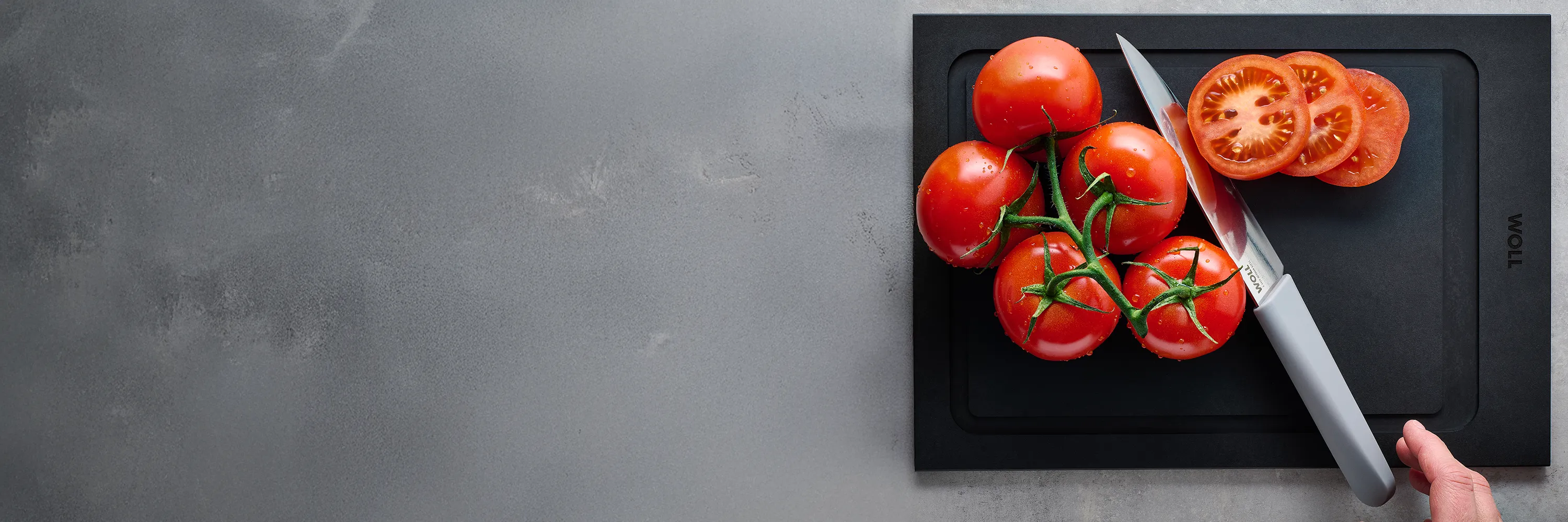 Mit dem Messer der Serie Cutting Edge werden Cherrytomaten auf einem Schneidebrett der Serie Cut & Serve halbiert.